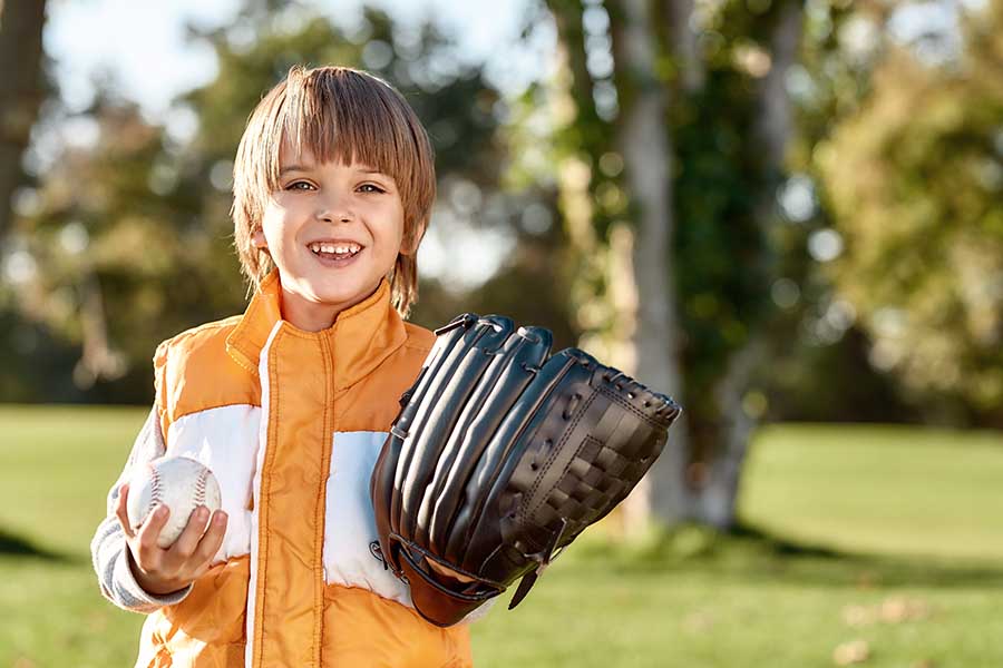 Employee Benefits - Smiling Little Boy Getting Ready to Play Baseball in the Park on a Sunny Day