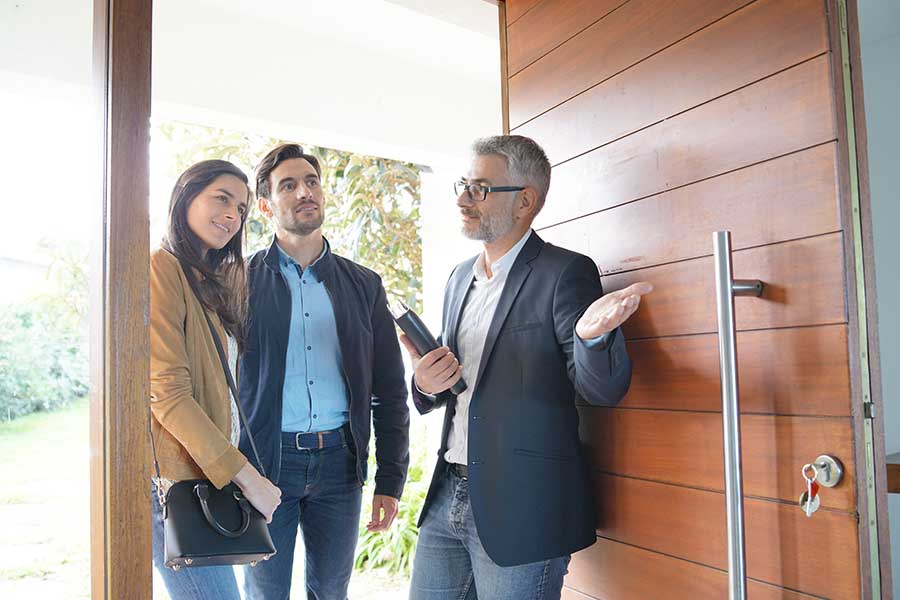 Personal Insurance - Couple with Real-Estate Agent Walking through Front Door of Their New Modern High-End Home